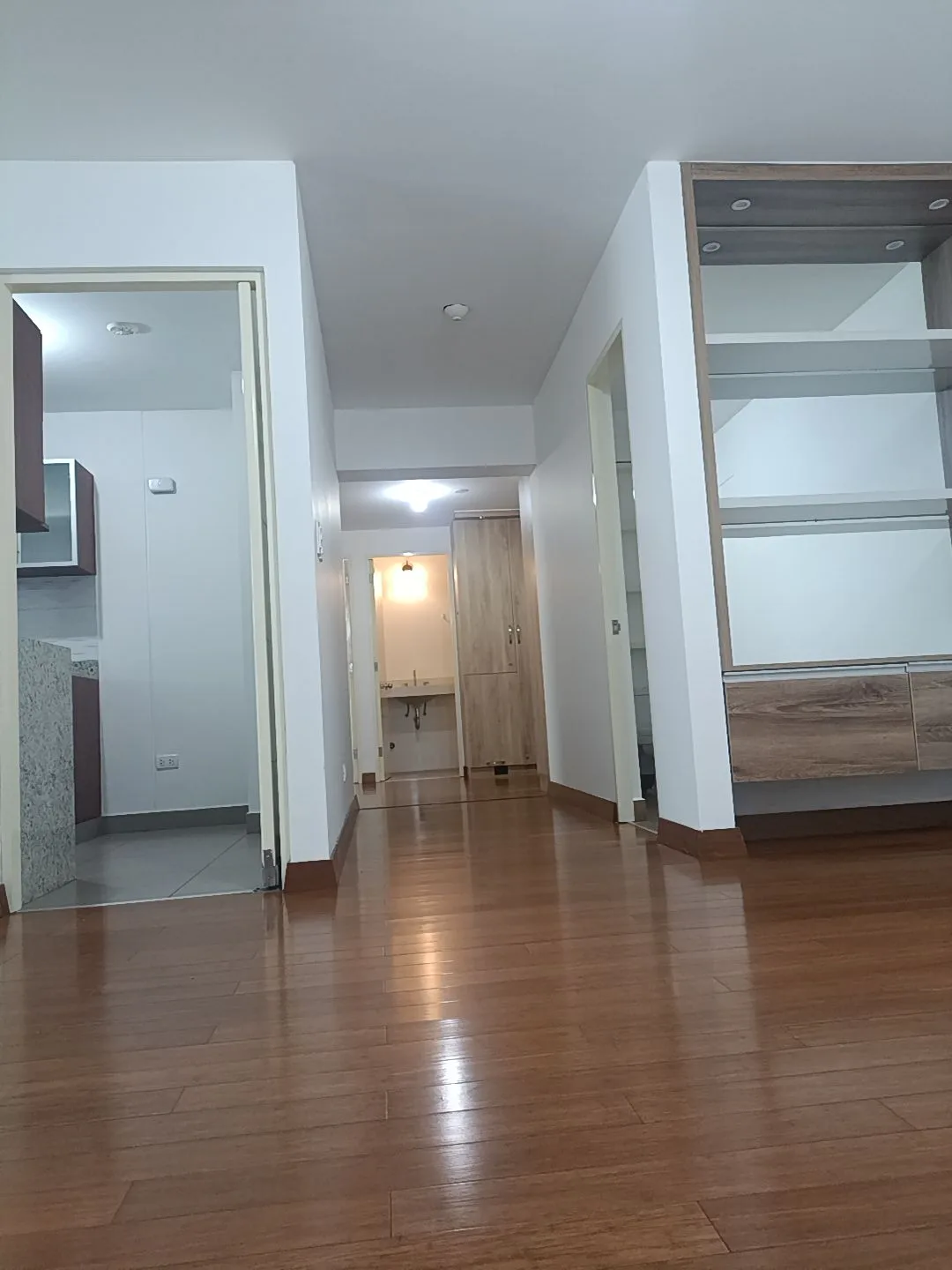 Sala con parquet y vista hacia la cocina con mesada de granito