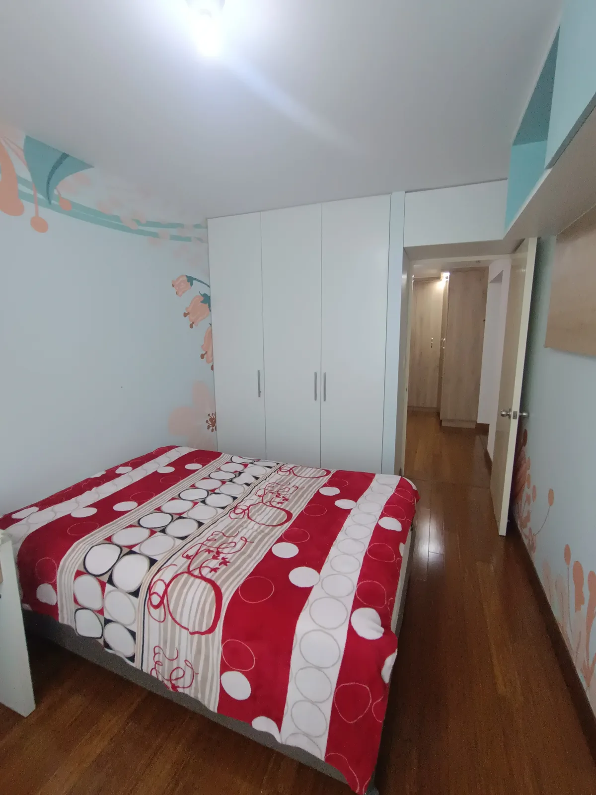 Dormitorio secundario con closet blanco empotrado y mural decorativo celeste