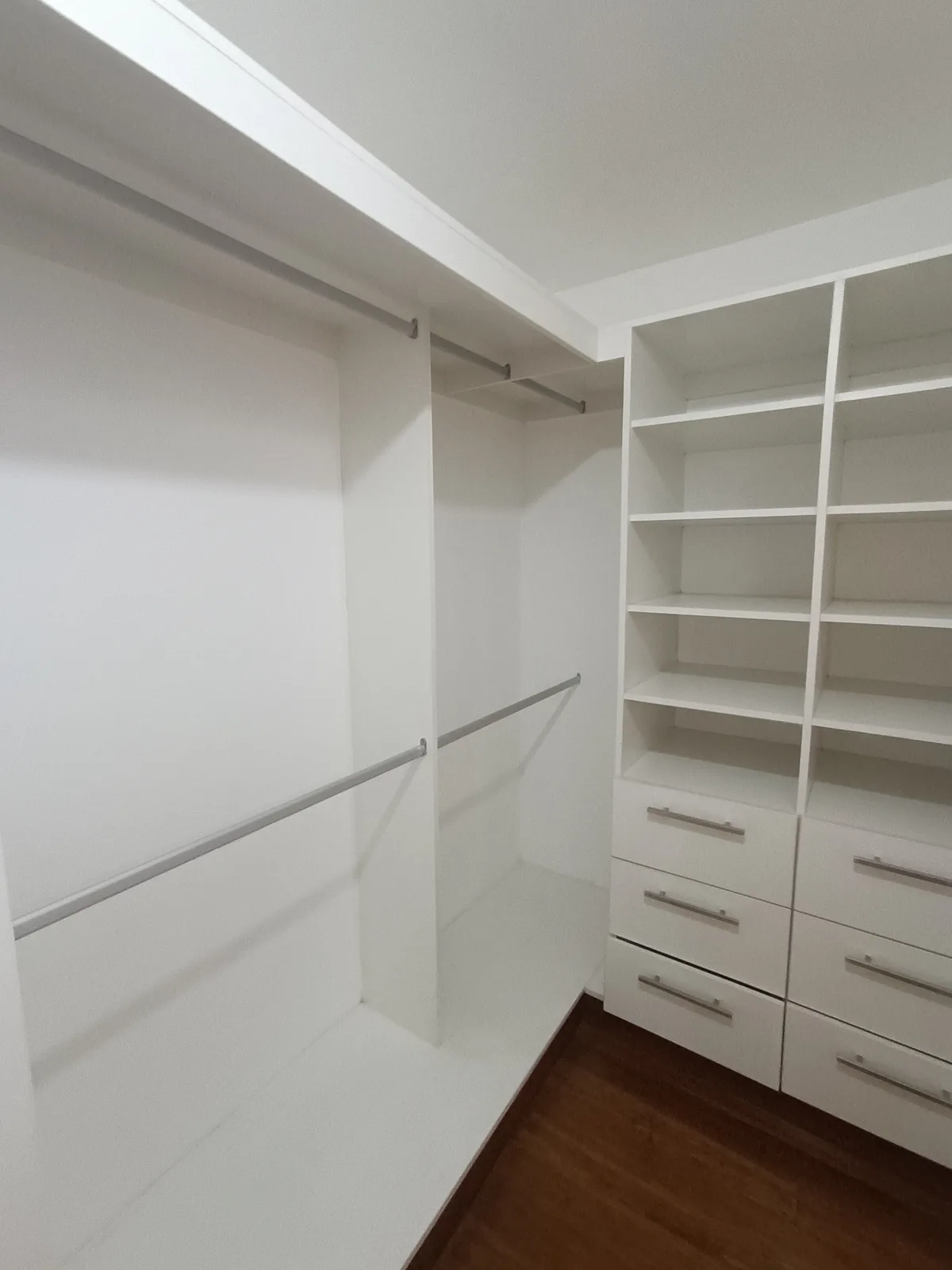 Vestidor blanco empotrado con doble barra y cajonera sobre piso de parquet