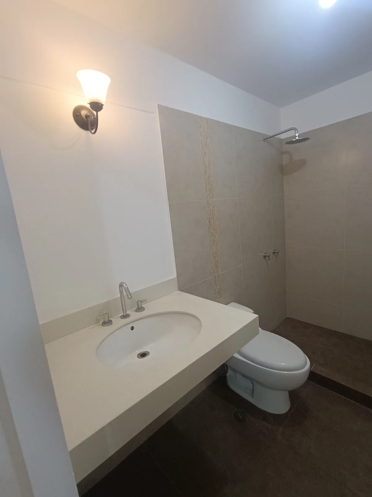 Bano con mesada blanca, grifera cromada y ducha de lluvia con detalle de mosaico